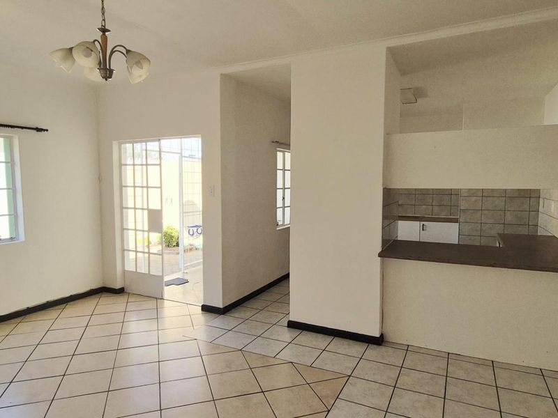 Open plan living area featuring tiled flooring, a kitchen breakfast bar with tiled backsplash, and direct access to an outdoor patio area.