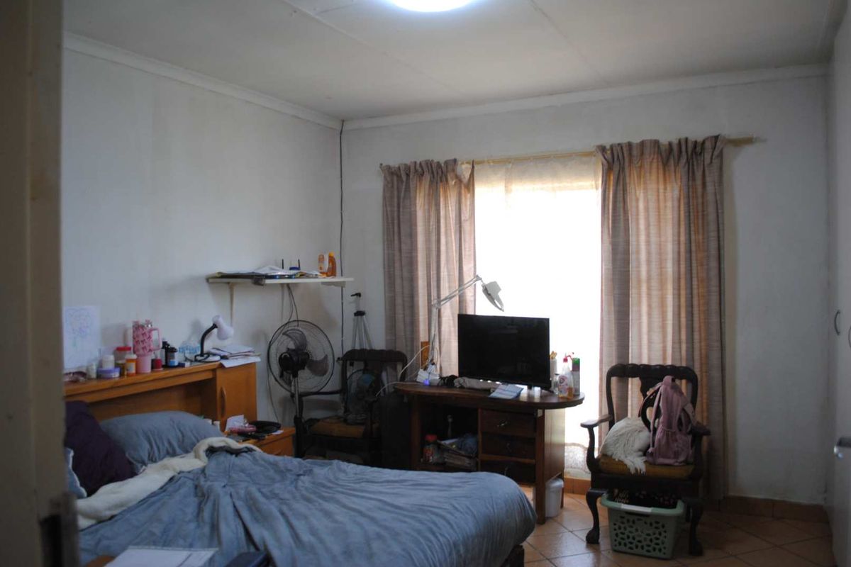A bedroom featuring tiled flooring, a window with curtain tracks, and a ceiling-mounted light fixture.