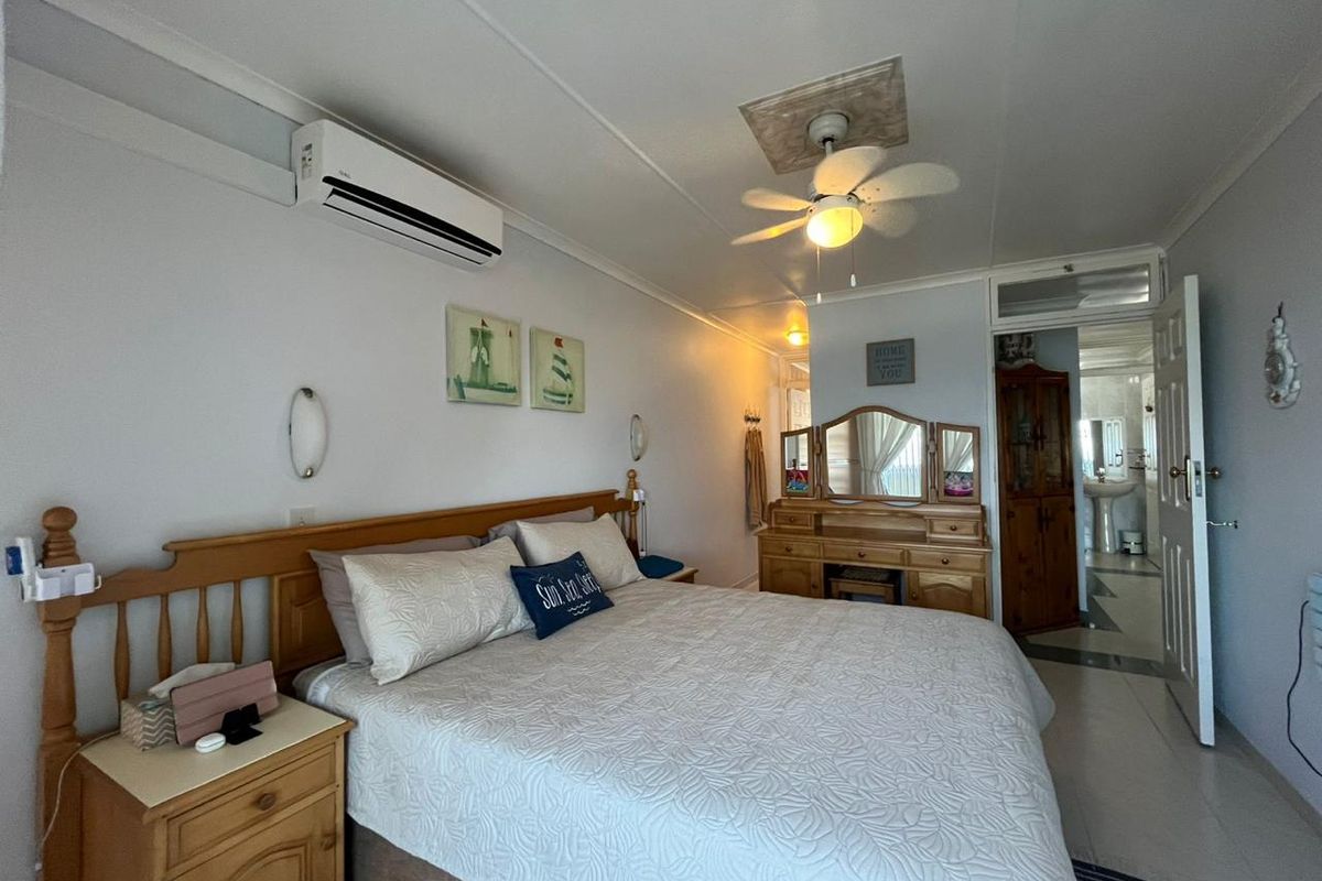 A well-maintained bedroom featuring a ceiling fan, split-system air conditioning, and direct access to an en-suite bathroom with tiled flooring throughout.