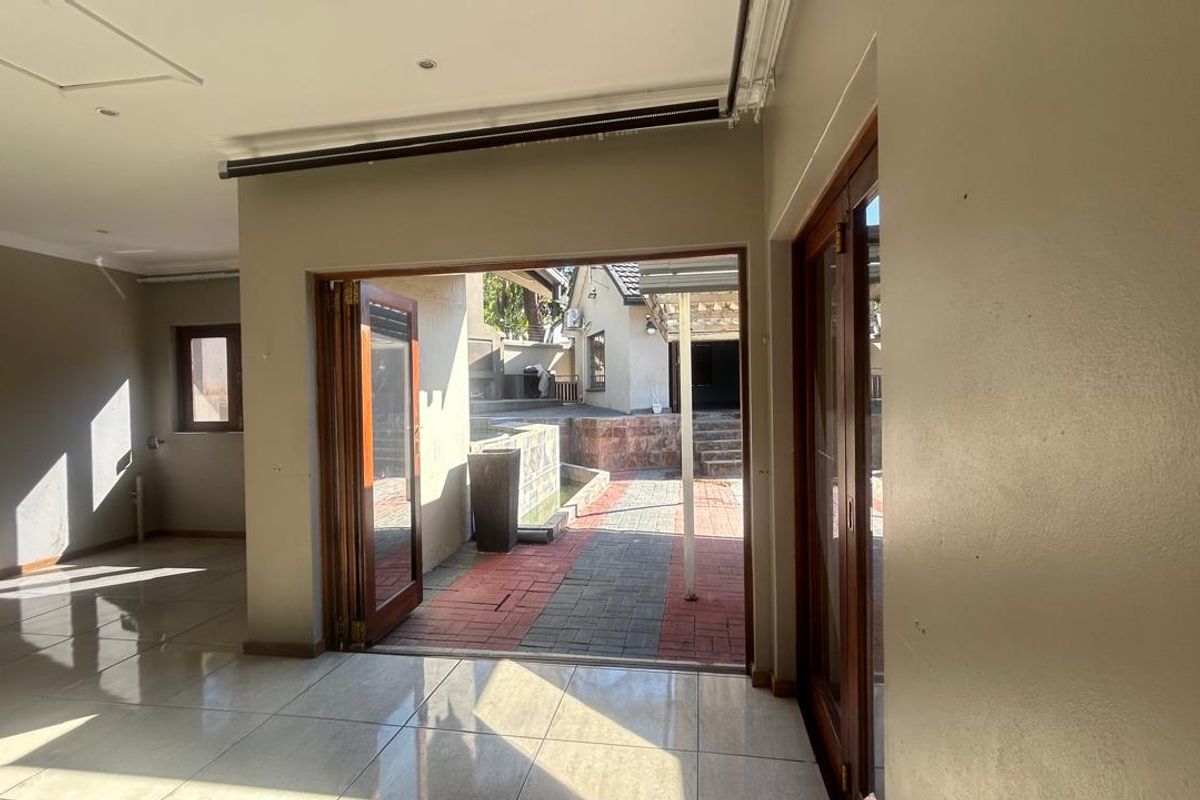 Spacious living area featuring neutral tiled flooring and large timber bi-fold doors opening onto a paved outdoor patio space.