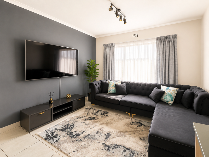 A well-maintained living room featuring a dark grey accent wall, tiled flooring, and modern track lighting, creating a comfortable and contemporary living space.