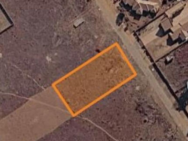 An aerial view of a vacant residential plot of land, highlighting the property boundaries in a developing neighborhood.