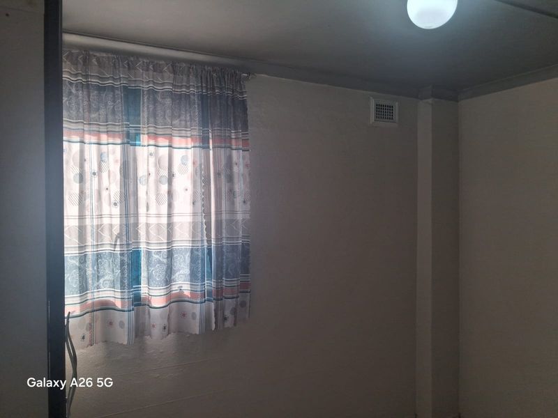 An empty bedroom featuring a ventilation grille and ceiling cornice, requiring cosmetic updates to improve the overall aesthetic and appeal.