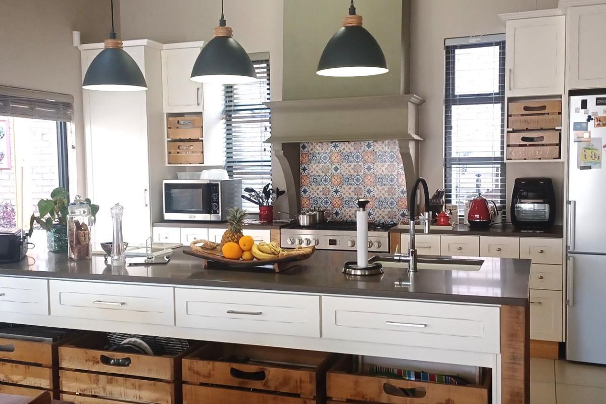 A well-appointed kitchen featuring a large central island with stone countertops, custom cabinetry, decorative tile backsplash, and integrated stainless steel appliances.