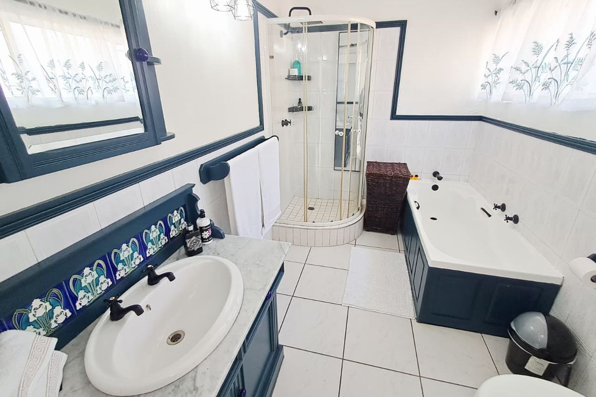 A well-maintained bathroom featuring a vanity with marble countertop, a separate shower enclosure, and a bathtub with dark blue paneling.