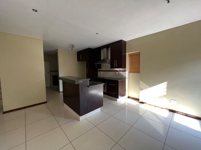 A functional kitchen featuring dark wood cabinetry, stone countertops, a breakfast bar, and tiled flooring, offering a clean and neutral space for culinary activities.