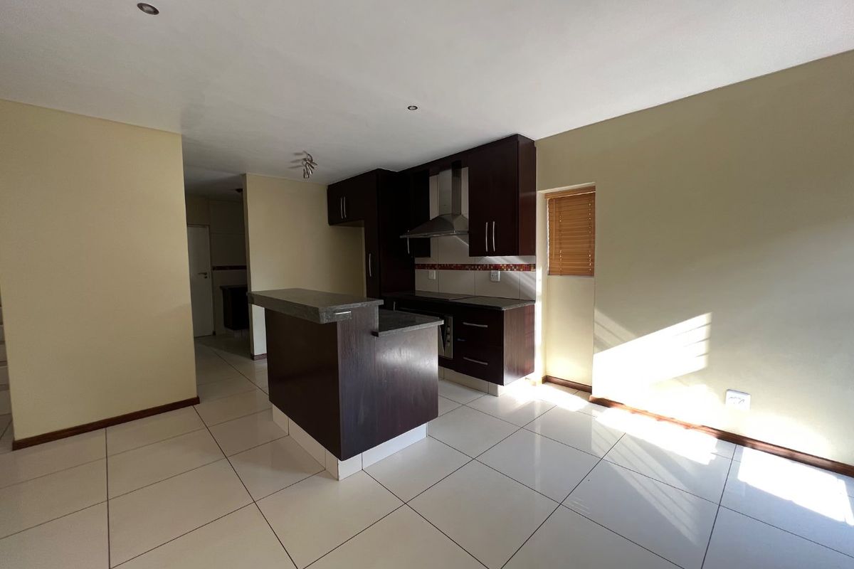 A functional kitchen featuring dark wood cabinetry, stone countertops, a breakfast bar, and tiled flooring, offering a clean and neutral space for culinary activities.