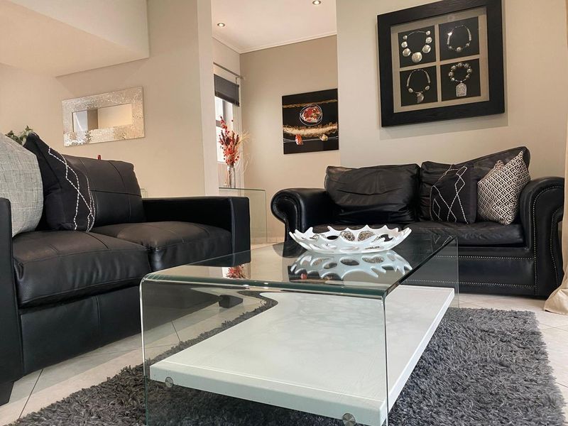 A well-maintained living room featuring neutral wall tones, tiled flooring, and recessed downlighting, creating a comfortable and inviting atmosphere.