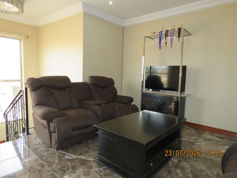 A living room area featuring polished marble-look floor tiles, decorative ceiling cornicing, and a wrought iron staircase railing.
