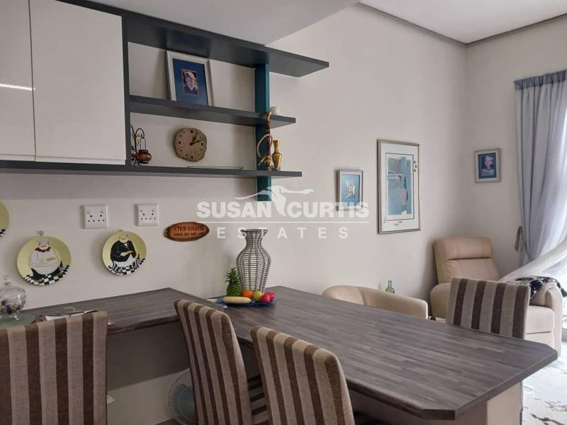 Open plan living area featuring built-in shelving and a functional laminate workspace or dining surface.
