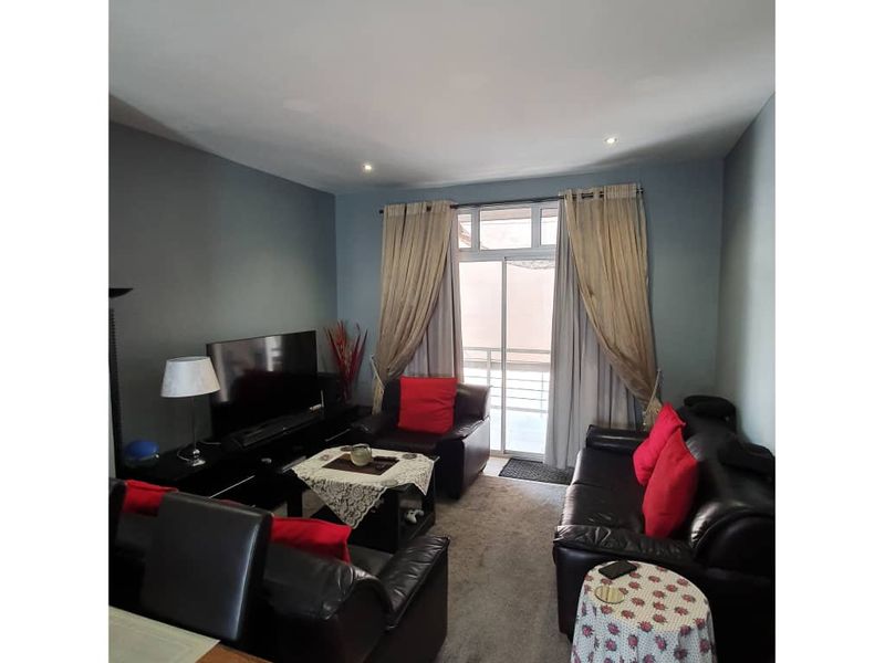 A living room featuring tiled flooring, recessed downlighting, and a sliding glass door providing access to an attached balcony.