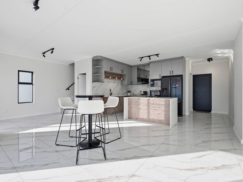 Modern open-plan living area featuring high-end marble-look floor tiles, a contemporary kitchen with island, and sleek track lighting throughout.
