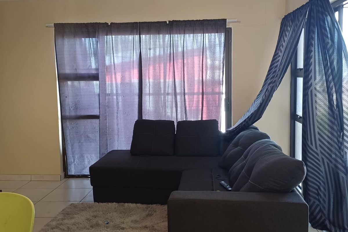 A living room area featuring tiled flooring and large sliding glass doors that provide access to an outdoor space.