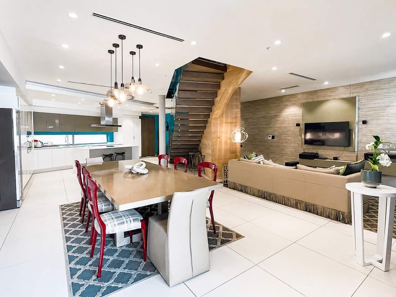 Spacious open-plan living, dining, and kitchen area featuring a modern timber staircase, sleek cabinetry, and high-end finishes in a contemporary penthouse setting.