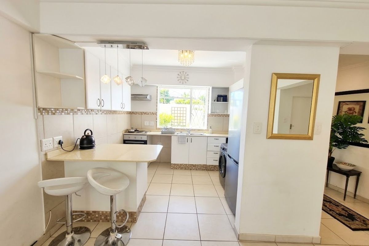 A functional kitchen featuring built-in cabinetry, a breakfast bar, tiled backsplash, and integrated appliances, with a clean layout and tiled flooring throughout.