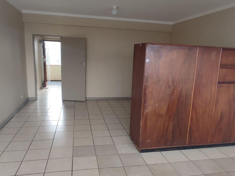 A spacious, empty living area featuring neutral tiled flooring and plain walls, offering a blank canvas for potential interior design and renovation.