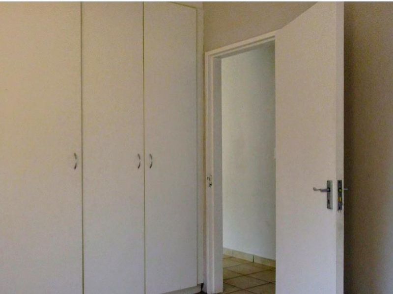 A bedroom interior featuring built-in cupboards and a doorway leading to an adjacent tiled space.