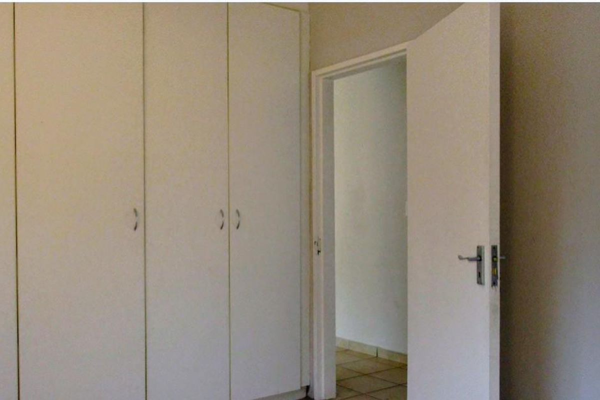 A bedroom interior featuring built-in cupboards and a doorway leading to an adjacent tiled space.