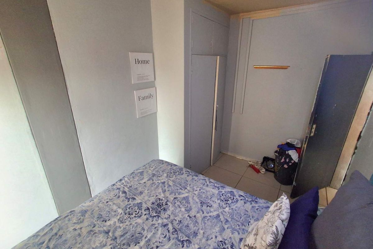 A compact bedroom featuring tiled flooring and a built-in cupboard, requiring some cosmetic updates to improve its overall appeal.