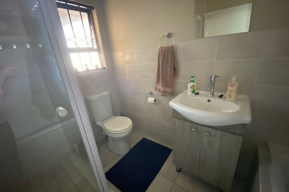 A functional bathroom featuring a shower enclosure, a vanity unit with a washbasin, and tiled finishes throughout.