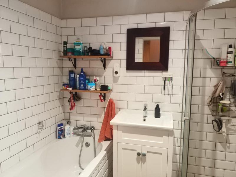 A functional bathroom featuring white subway tile wall cladding, a vanity basin, a bathtub, and a separate shower enclosure.
