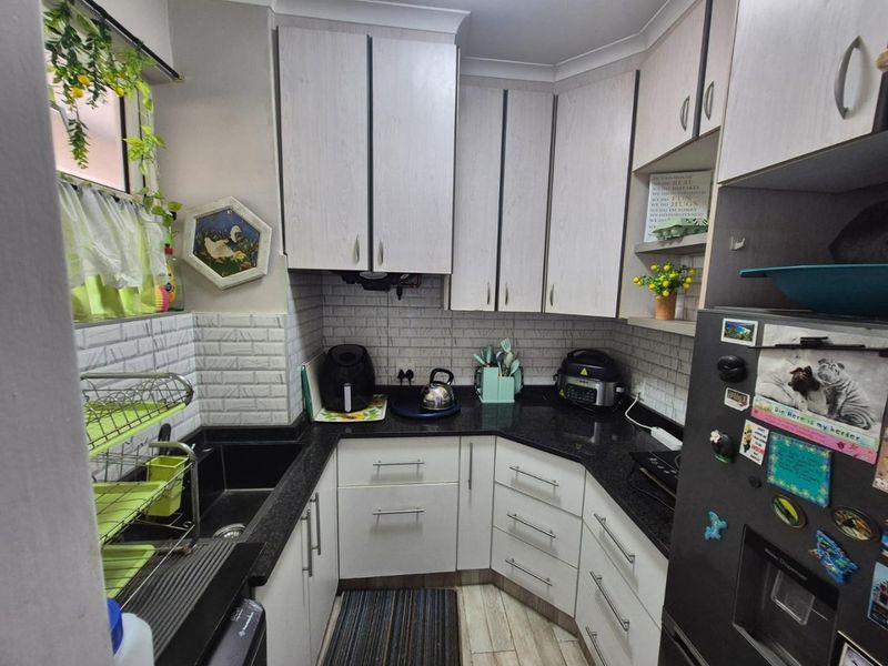 A compact kitchen featuring white cabinetry, dark granite countertops, and a textured subway tile backsplash, providing a functional and well-organized cooking space.