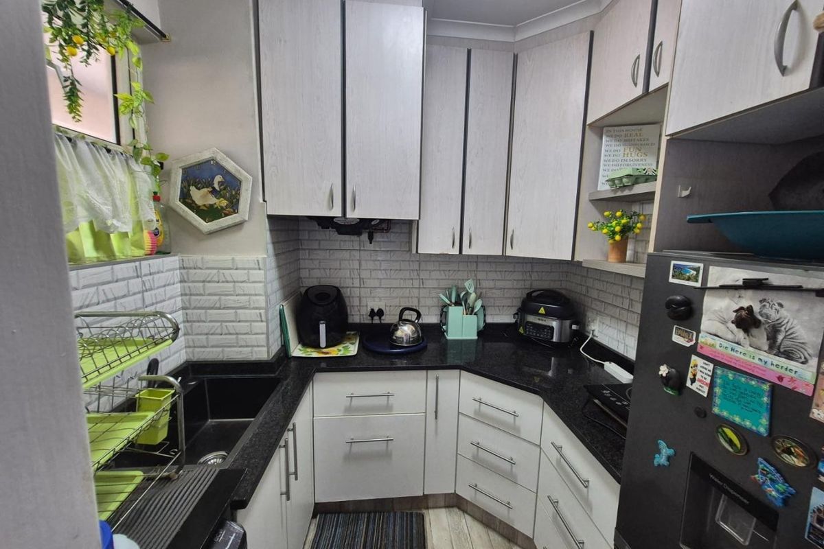 A compact kitchen featuring white cabinetry, dark granite countertops, and a textured subway tile backsplash, providing a functional and well-organized cooking space.