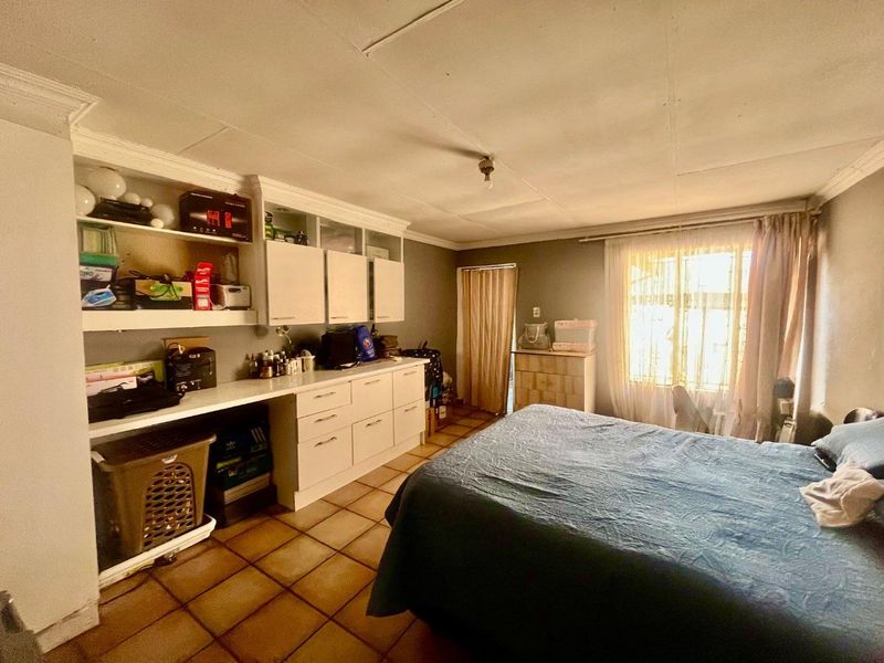 Bedroom featuring built-in cabinetry, tiled flooring, and ceiling cornice. The space requires cosmetic updates to improve the overall finish and condition.