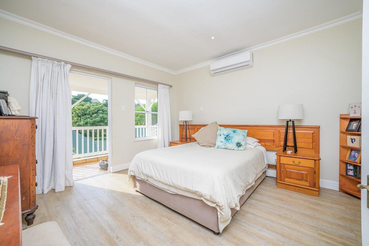 A well-maintained bedroom featuring laminate flooring, crown molding, a built-in headboard, and direct access to a private balcony via sliding glass doors.