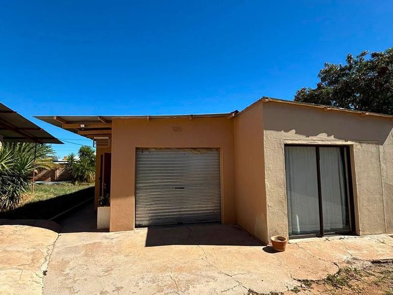 Exterior view of a property featuring a roller shutter garage door, a sliding glass door entrance, and a concrete driveway.