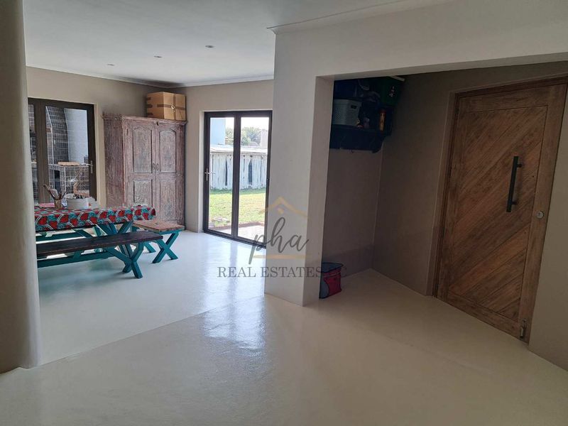 Open plan living area featuring smooth epoxy flooring, recessed lighting, and direct access to the outdoor patio through sliding glass doors.