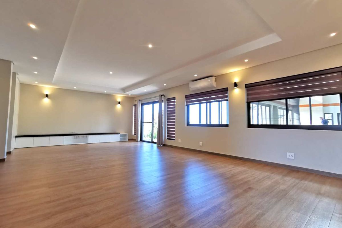 Spacious living area featuring wood-look tile flooring, recessed ceiling lighting, built-in cabinetry, and wall-mounted air conditioning unit.