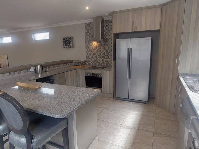 Modern open-plan kitchen featuring granite countertops, built-in oven, gas hob, and ample cabinetry, seamlessly flowing into the adjacent living area.