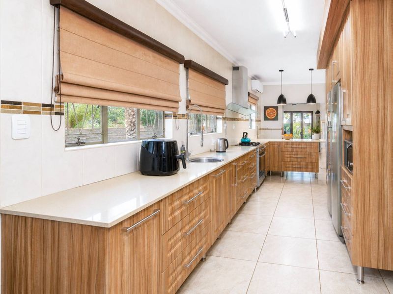 A well-maintained kitchen featuring wood-grain cabinetry, stone countertops, integrated appliances, and tiled flooring, offering a functional and modern workspace.