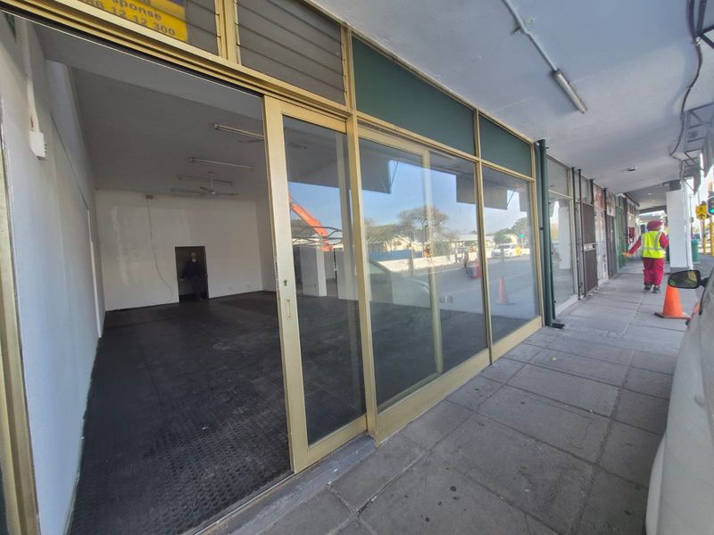 Street-level commercial storefront featuring large sliding glass doors and an open-plan interior space with paved sidewalk access.