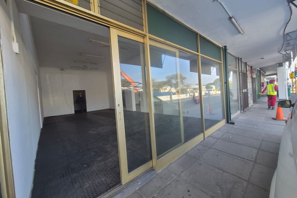Street-level commercial storefront featuring large sliding glass doors and an open-plan interior space with paved sidewalk access.