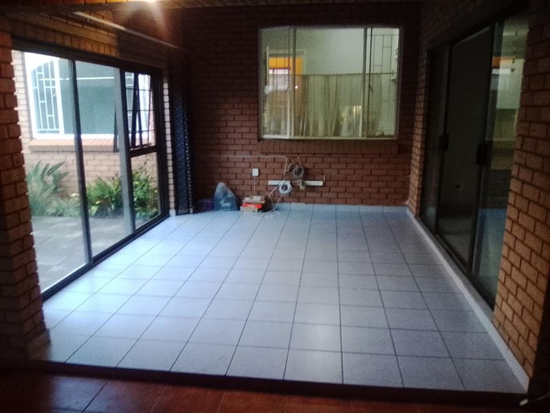 An enclosed patio area featuring exposed brick walls, tiled flooring, and large sliding glass doors providing access to the exterior.