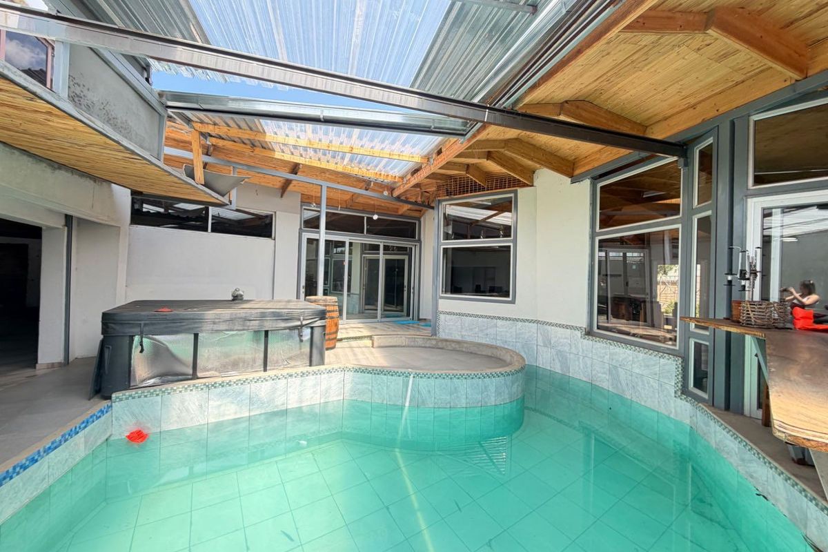 Indoor swimming pool area featuring a translucent roof, exposed timber trusses, and tiled surrounds, providing a sheltered space for year-round recreation.