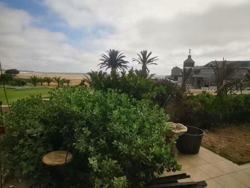 A covered patio area overlooking a garden with coastal views in the distance.