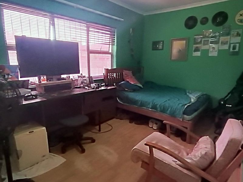 A bedroom featuring laminate flooring and large windows with venetian blinds, offering a functional space ready for personalization.