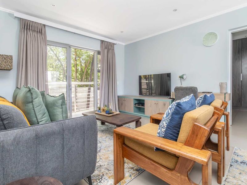 A bright and well-maintained living room featuring tiled flooring, recessed lighting, and a sliding glass door providing access to an outdoor area.