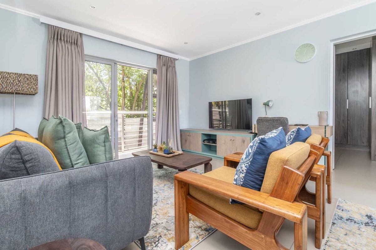 A bright and well-maintained living room featuring tiled flooring, recessed lighting, and a sliding glass door providing access to an outdoor area.