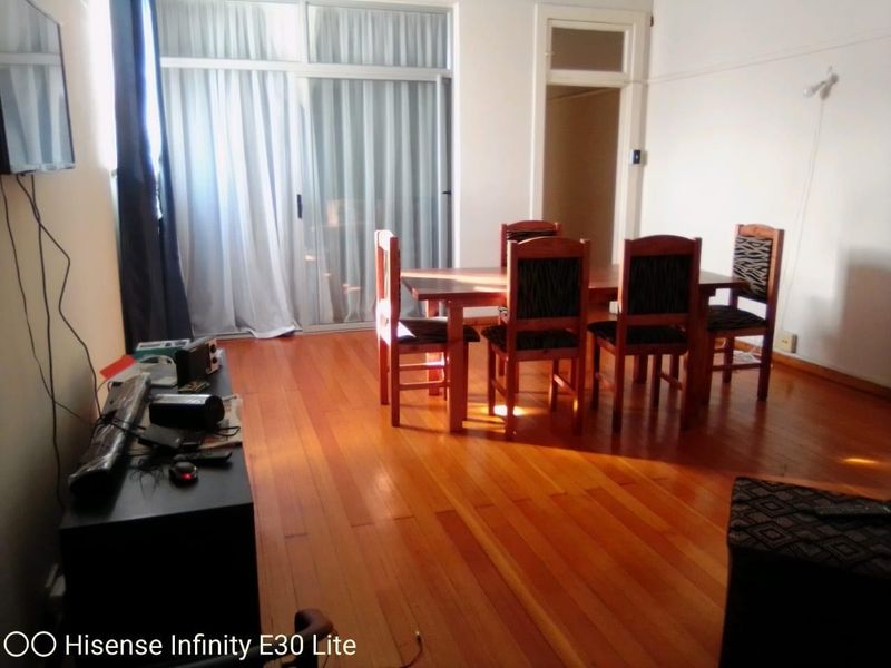 A living and dining area featuring polished hardwood flooring and a large sliding glass door providing access to the exterior.