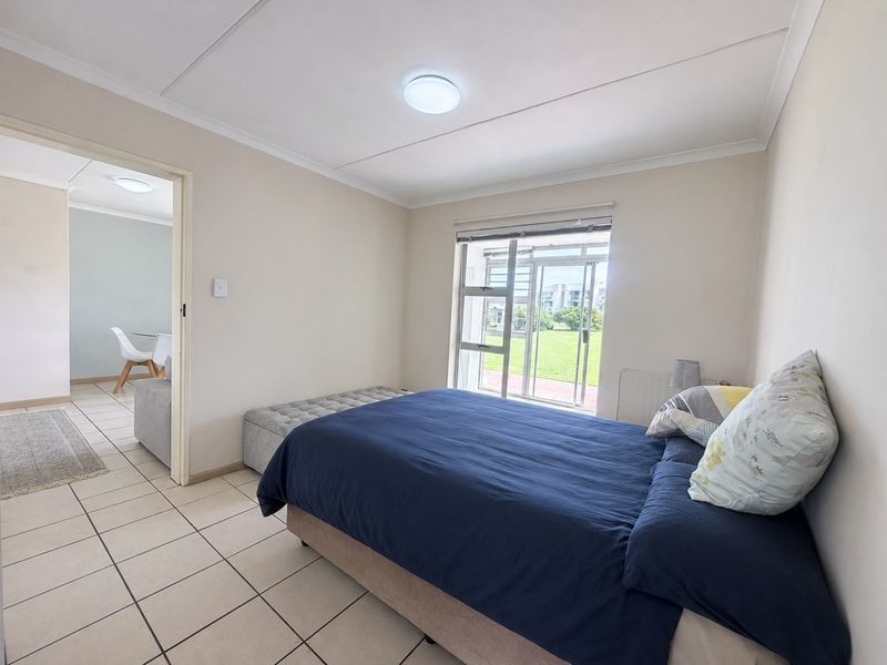 A bright bedroom featuring tiled flooring, a coved ceiling, and a sliding glass door providing access to the exterior.