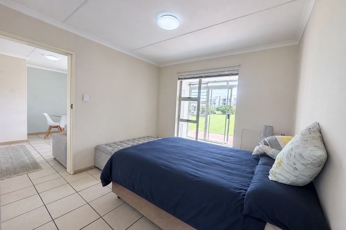 A bright bedroom featuring tiled flooring, a coved ceiling, and a sliding glass door providing access to the exterior.