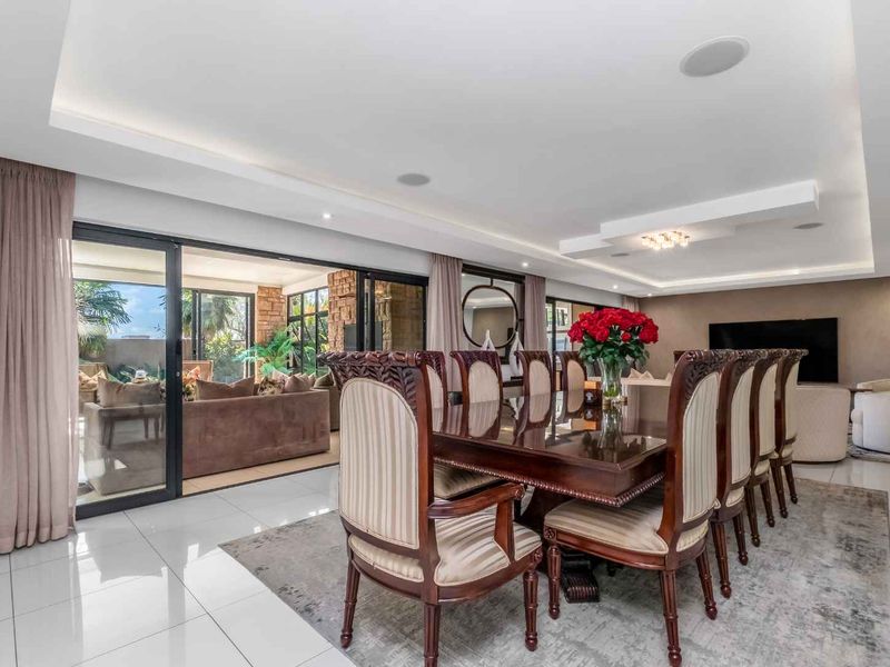 Spacious open-plan dining area featuring high-gloss floor tiles, recessed ceiling lighting, and large sliding glass doors providing seamless access to the outdoor patio.