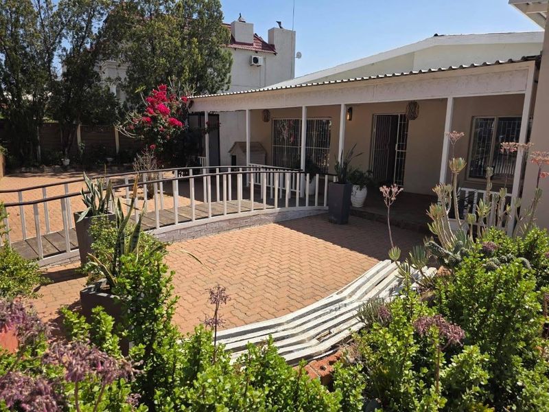 A covered patio area featuring brick paving and a decorative wooden bridge, providing a functional outdoor space for relaxation.
