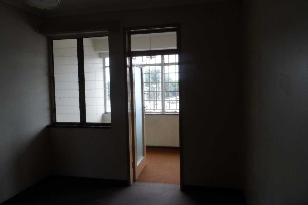 An empty bedroom featuring carpet flooring and direct access to an adjoining balcony through a glass-paneled door.
