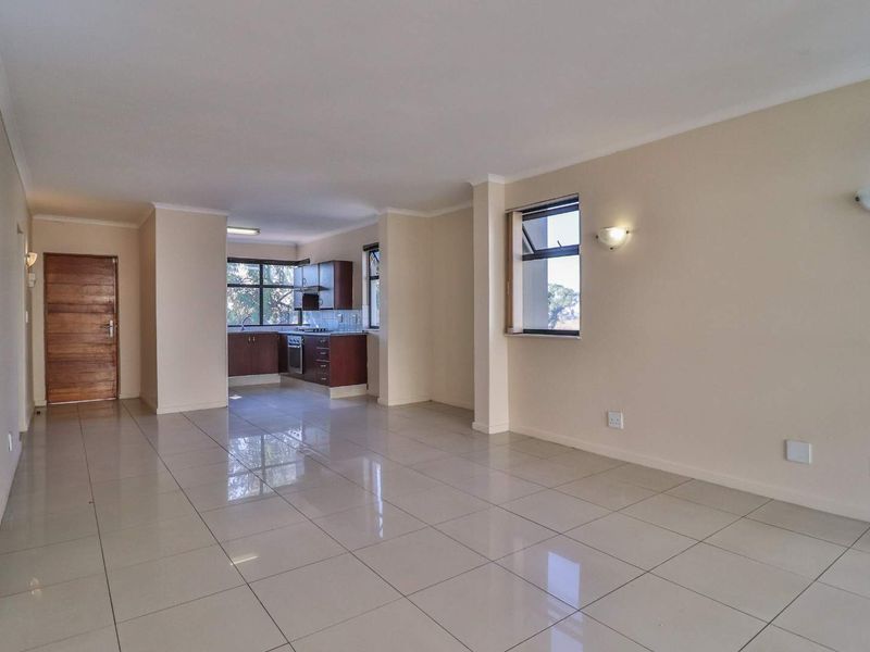 Spacious open-plan living area featuring tiled floors and a functional kitchen with built-in cabinetry, oven, and hob.