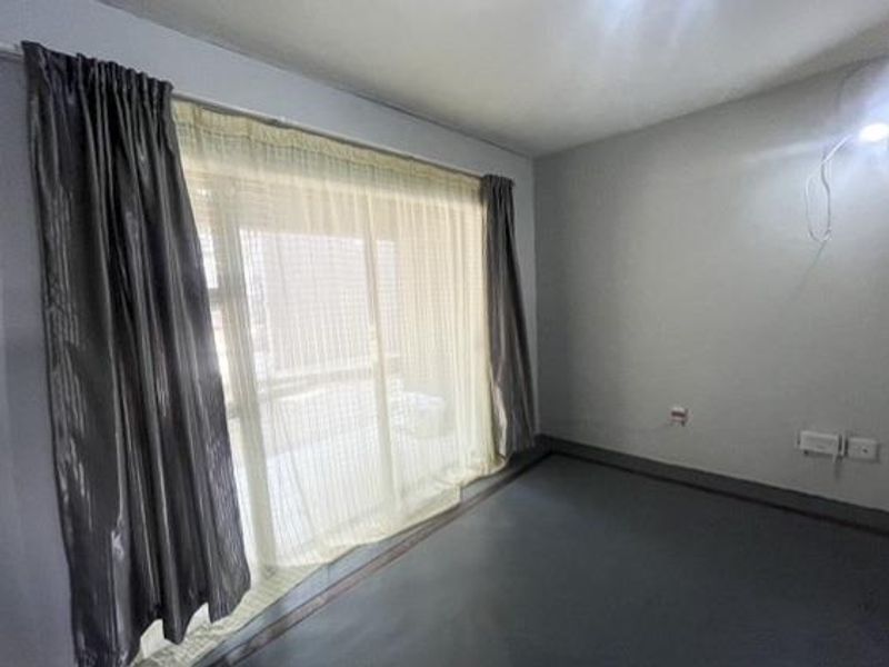 A vacant bedroom featuring a large sliding glass door with curtain tracks and neutral wall finishes.